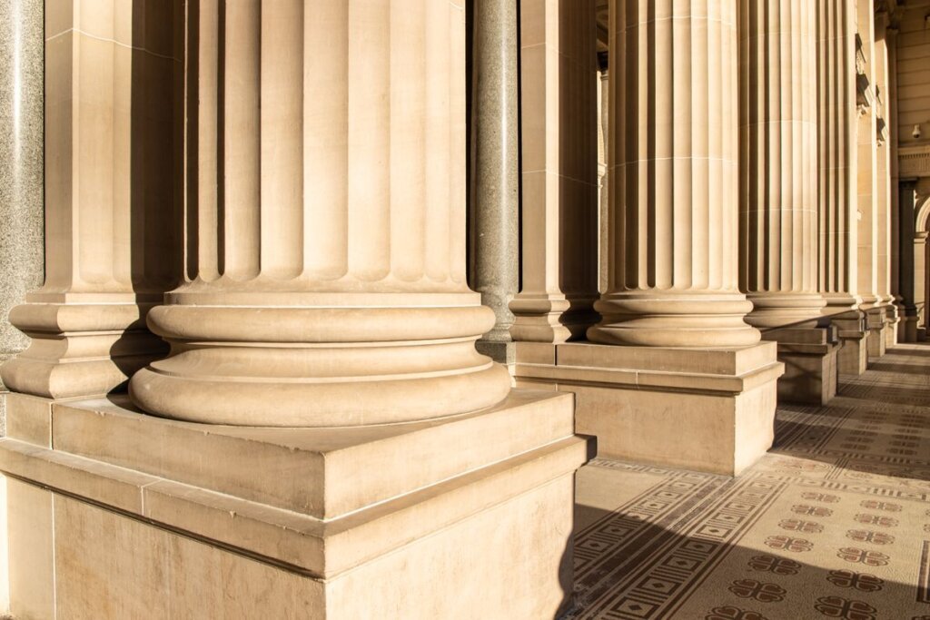 Row of classical stone columns in warm sunlight, representing the seven pillars that support lasting personal change